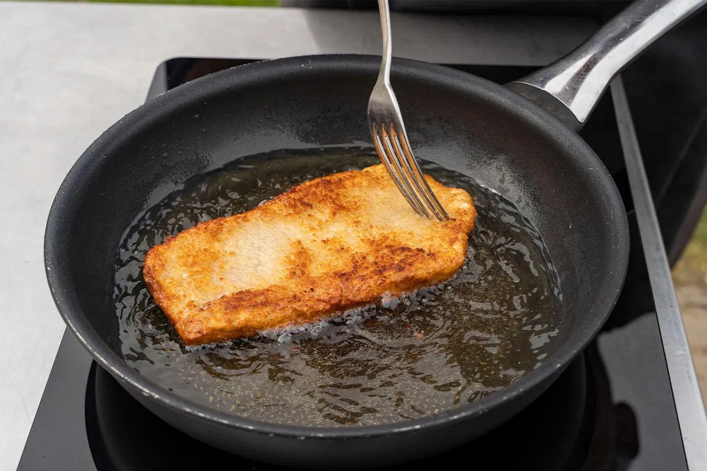 Goudbruine krokante korst op de gebakken kalfsschnitzel in de pan