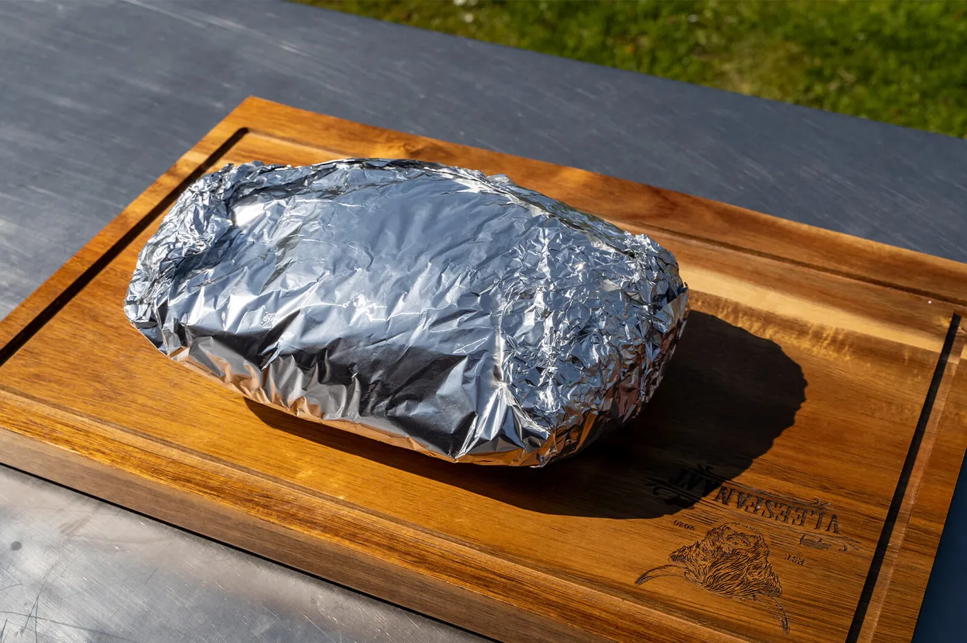 Het vlees ingepakt in aluminiumfolie om door te garen