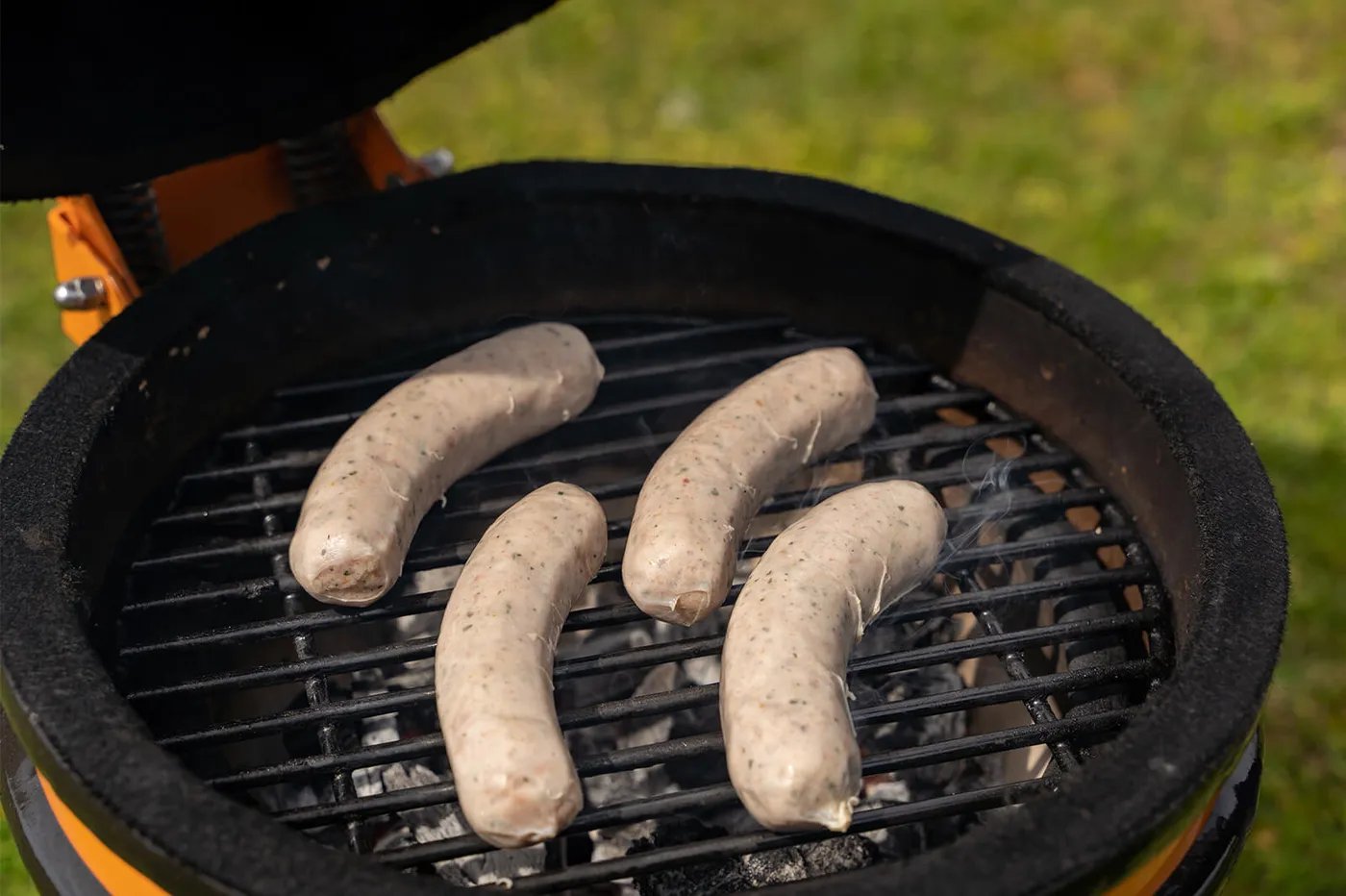 Rustieke worstjes die op het rooster van de barbecue liggen boven direct vuur