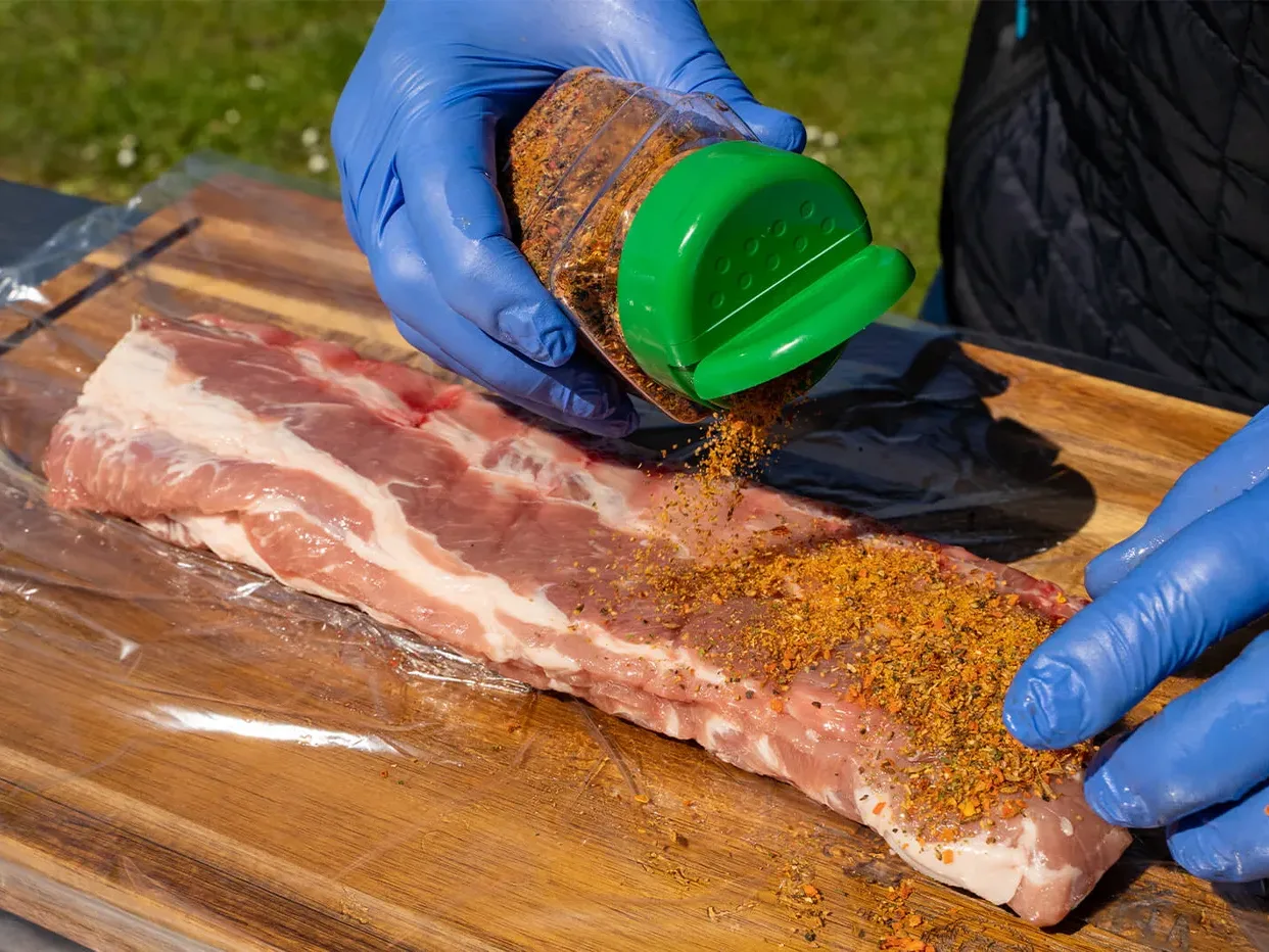 BBQ kruiden (rub) over de spareribs strooien