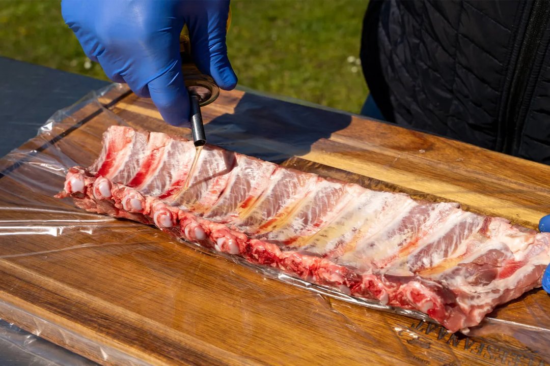 Olijfolie op de ongemarineerde spareribs schenken